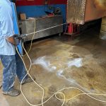 Technician pressure washing industrial heat exchanger at St. Louis radiator repair facility