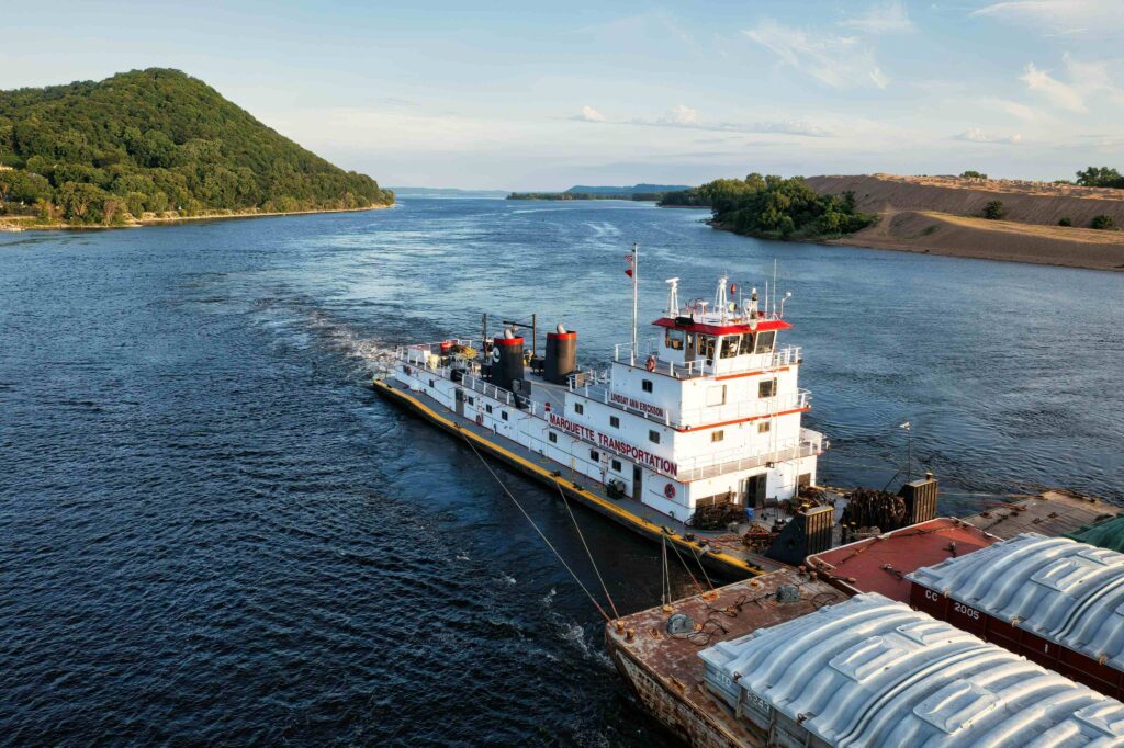 Tug boat navigating the Mississippi River near Paducah, KY, transporting cargo barges, with visible oil cooler systems on deck.
